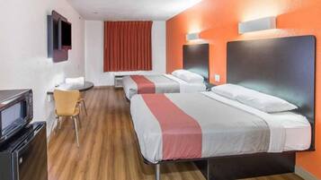 A hotel room with two beds, a desk, a chair, and a television.