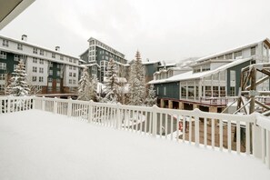 A snow-covered outdoor area with a white fence, buildings with multiple windows, and snow-laden trees. - Resort Center 5004 | Ski-In/Ski-Out | Pool & Hot Tub Access | Fireplace | Elevator | 1,700 Sq Ft (Park City)