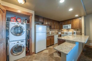 A compact kitchen with built-in appliances, wooden cabinets, and a granite countertop. - Resort Center 5009 | Ski-In/Ski-Out | Pool & Hot Tub Access | Bright & Sunny | 2 Baths | King Bed (Park City)