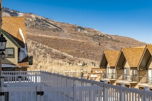A row of chalet-style cabins with a wooden deck and a white picket fence in the foreground. - Resort Center 5030 | Ski-In/Ski-Out | Pool & Hot Tub Access | Balcony w/ Ski Run Views | Fireplace (Park City)