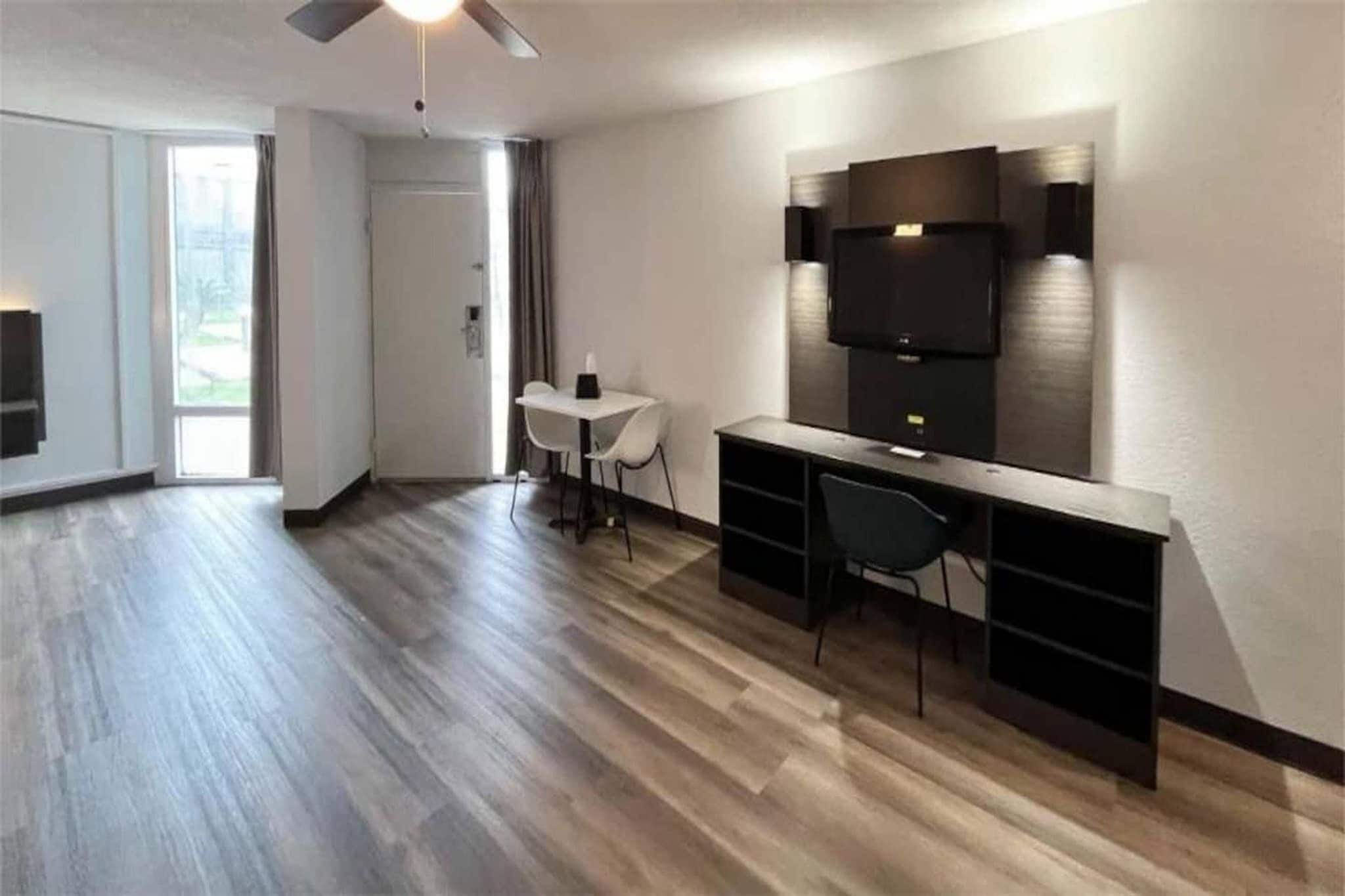 A modern living space with a dining area, a flat-screen TV mounted on the wall, and a ceiling fan.