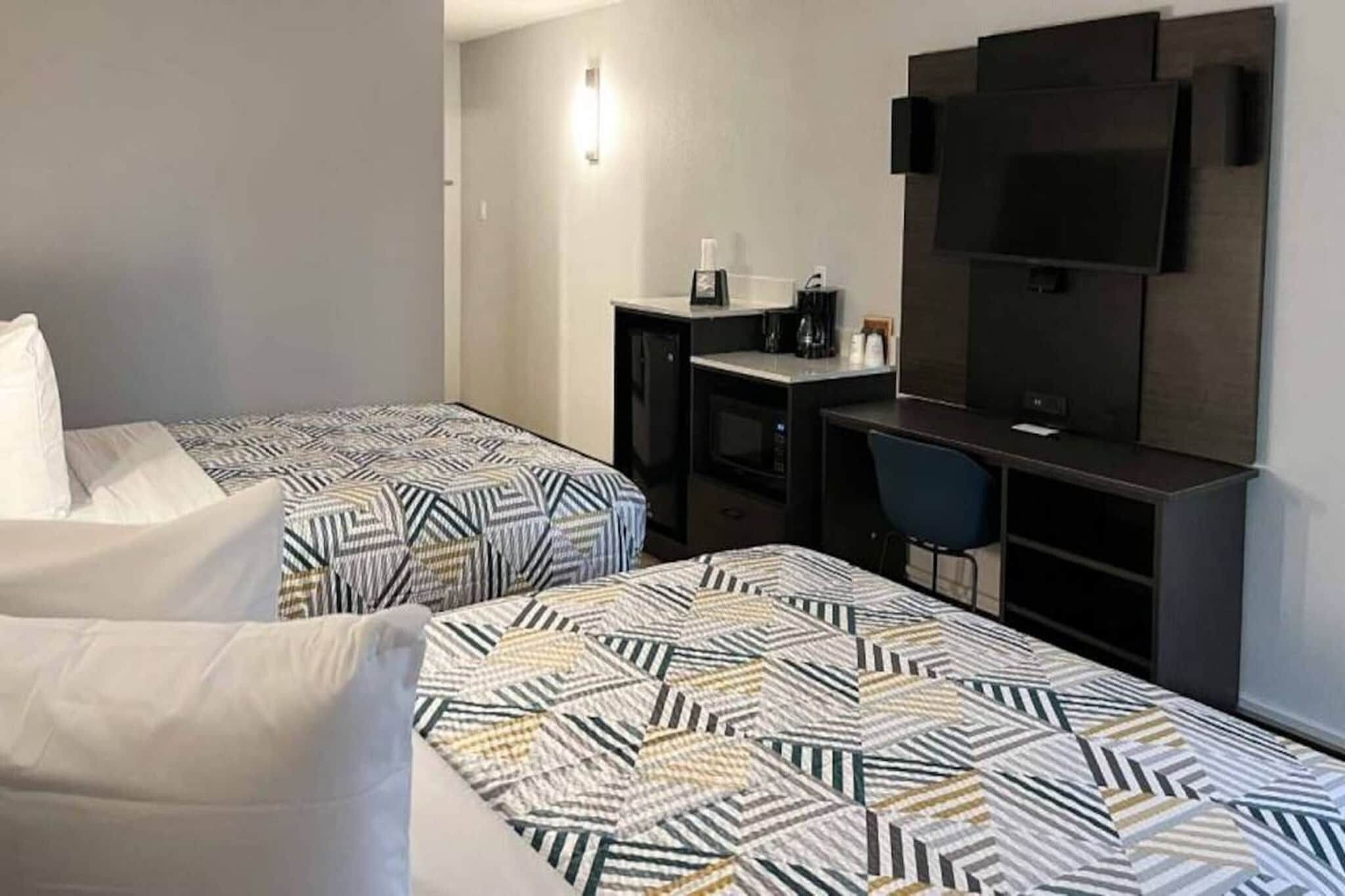 Habitació d'hotel amb dos llits, una taula de treball, una cadira, televisió i microones.