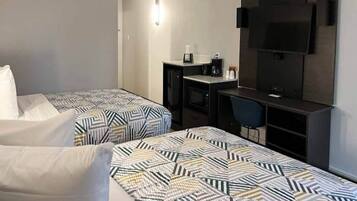 Habitació d'hotel amb dos llits, una taula de treball, una cadira, televisió i microones.