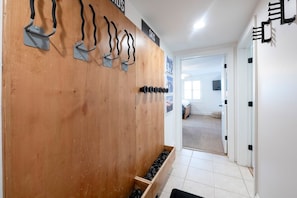 A hallway with a wooden wall, metal hooks, and a shoe rack. - Resort Center 5034 | Ski-In/Ski-Out | Pool & Hot Tub Access | Ski Mudroom | Fireplace | Sleeps 8 (Park City)