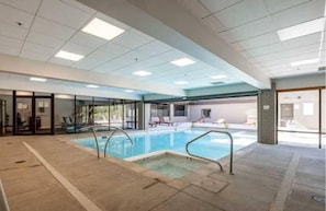 An indoor swimming pool with clear glass walls, a tiled floor, and a ceiling with recessed lighting. - Resort Center 5052 | Ski-In/Ski-Out | Pool & Hot Tub Access | Mtn View Deck | Fireplace | A/C (Park City)