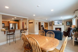 A spacious living area with a fireplace, a television, and a dining table with chairs. - Resort Center 5052 | Ski-In/Ski-Out | Pool & Hot Tub Access | Mtn View Deck | Fireplace | A/C (Park City)