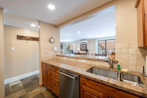 A kitchen with granite countertops, a stainless steel sink, wooden cabinets, and a dishwasher. - Resort Center 5052 | Ski-In/Ski-Out | Pool & Hot Tub Access | Mtn View Deck | Fireplace | A/C (Park City)