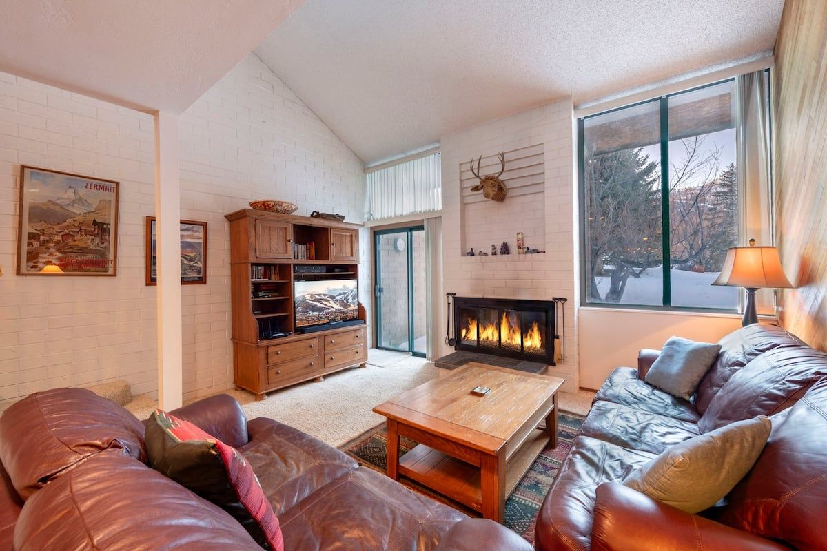 A cozy living room with a fireplace, leather sofas, and a wooden cabinet.