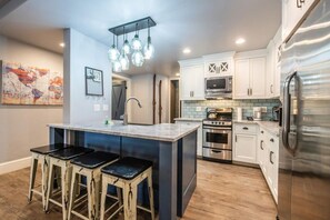 A modern kitchen with a central island, stainless steel appliances, and a hanging light fixture. - Resort Center 5000 | Ski-In/Ski-Out | Pool & Hot Tub Access | Steam Shower | Bunk Beds | Renovated (Park City)