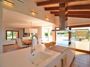 A modern kitchen with a large island, built-in appliances, and a view of the outdoor patio. - Cabin in Muro With Swimming Pool (Muro)