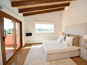 A bedroom with a large bed, a TV, a window, and a wooden ceiling. - Cabin in Muro With Swimming Pool (Muro)