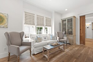 Ein Wohnzimmer mit einer Couch, zwei Sesseln, einem Couchtisch und einer Vitrine.