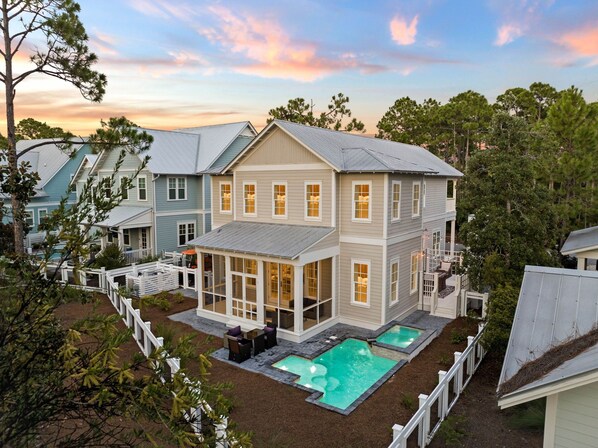 Ein zweigeschossiges Haus mit einer großen Terrasse und einem Swimmingpool.