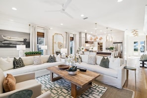 A modern living room with a sectional sofa, a coffee table, and a dining area. - Sleeps 20, Walk to Beach! Private Pool, LSV, & GULF Views! (Santa Rosa Beach)