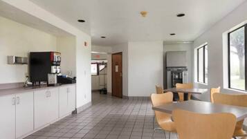 A spacious indoor area with a kitchen counter, a refrigerator, and a dining table with chairs.