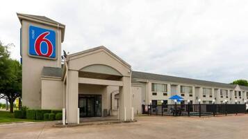 A 6 hotel with a modern entrance, a parking lot, and a fence.