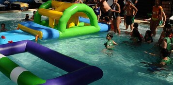 Una piscina con estructuras inflables y gente nadando.