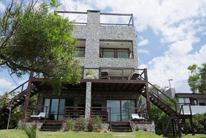 A modern two-story house with a stone facade, large windows, and a wooden staircase.