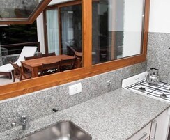 Una cocina con encimeras de granito, pileta de acero inoxidable y estufa a gas.
