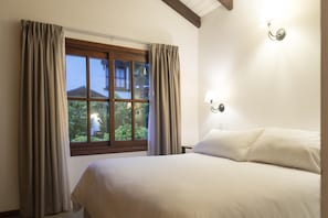 Una camera da letto con un letto grande, una finestra con tende e un lampadario a parete.