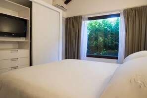 A hotel room with a bed, a television on a shelf, and a window with curtains. - Rincon del Duende (Mar de Las Pampas)