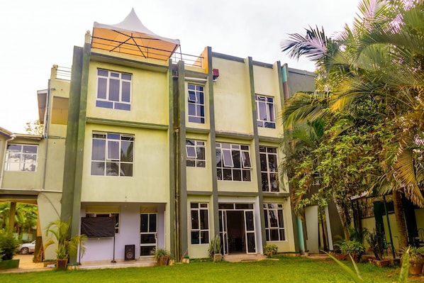 A multi-story building with a flat roof, large windows, and a covered outdoor area.
