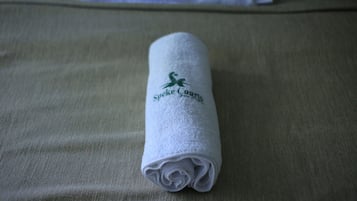 Toalha enrolada com logotipo em uma cama.