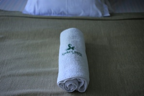 A rolled towel with a logo on a bed. - Speke Courts Hotel Jinja (Jinja)