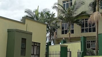 A building with a flat roof, multiple windows, and a green fence.