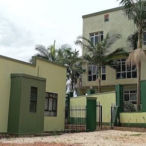 A building with a flat roof, multiple windows, and a green fence.