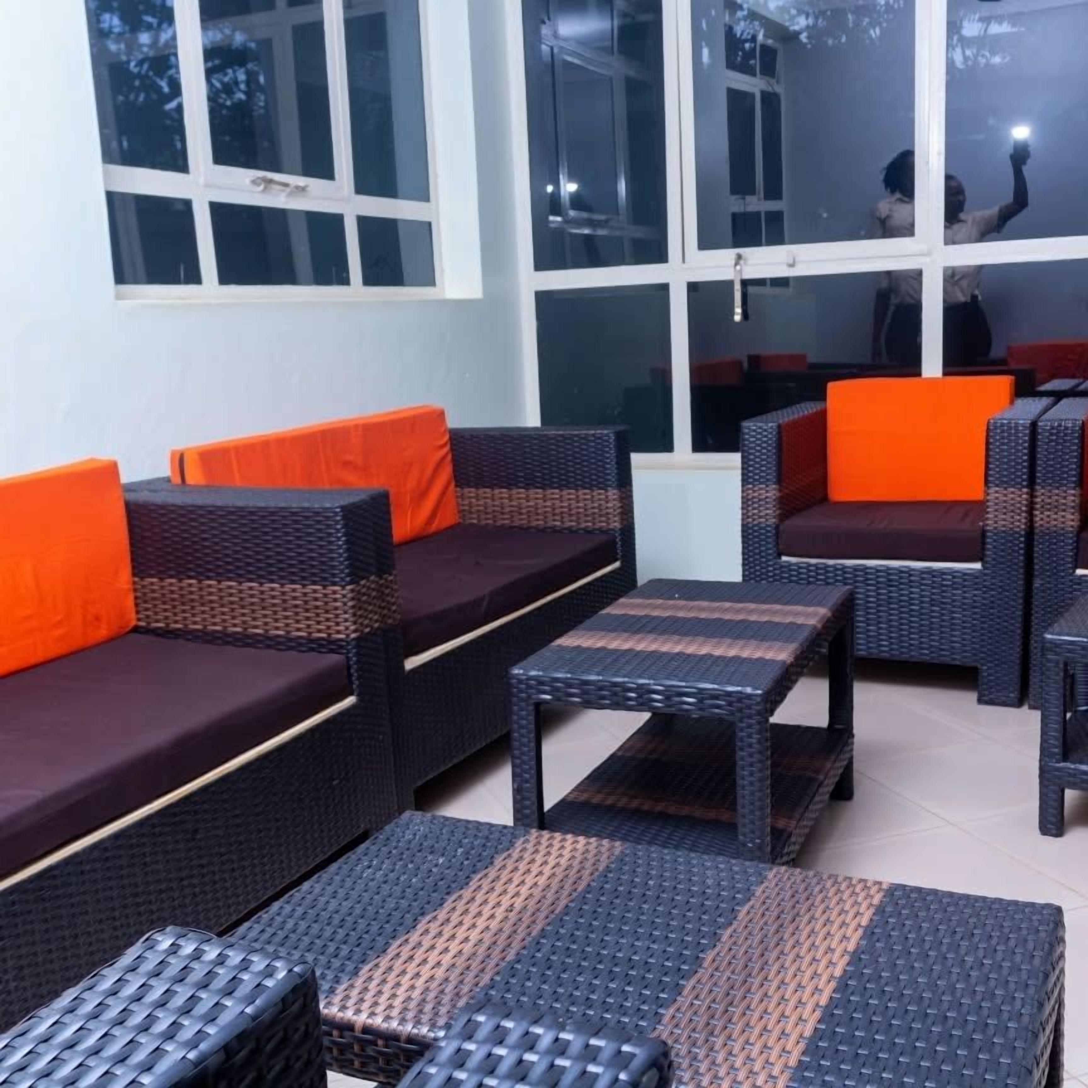 Une pièce meublée avec des meubles en osier, notamment des canapés et une table, agrémentée de coussins orange.