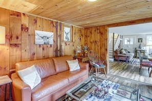 A wooden-paneled room with a leather sofa, a rocking chair, and a glass coffee table. - 1/2 Mi to Marina! Lake George Group Getaway (Diamond Point)