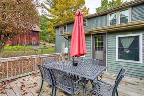 A patio with a table and chairs, an umbrella, and a house in the background. - 1/2 Mi to Marina! Lake George Group Getaway (Diamond Point)