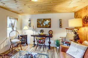 A cozy living room with a wooden ceiling, a dining table, chairs, a sofa, and a decorative wall piece. - 1/2 Mi to Marina! Lake George Group Getaway (Diamond Point)