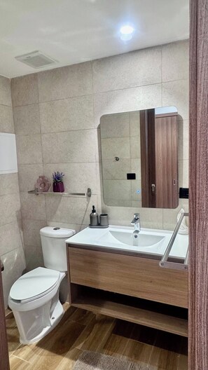 Een moderne badkamer met toilet, wastafel en spiegel.