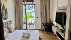 Ein Hotelzimmer mit Bett, Schreibtisch, Fernseher und Blick ins Freie.