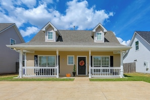 A two-story house with a front porch, a black front door, and a small garden area. - Walk to Texas A&M! Quiet Home w/ Fenced Yard (College Station)