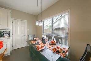 A dining area with a table set for four, a coffee bar, and a window with blinds. - Walk to Texas A&M! Quiet Home w/ Fenced Yard (College Station)