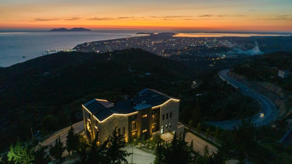 Un bâtiment à l’architecture moderne, situé sur une colline surplombant un paysage urbain côtier au crépuscule.