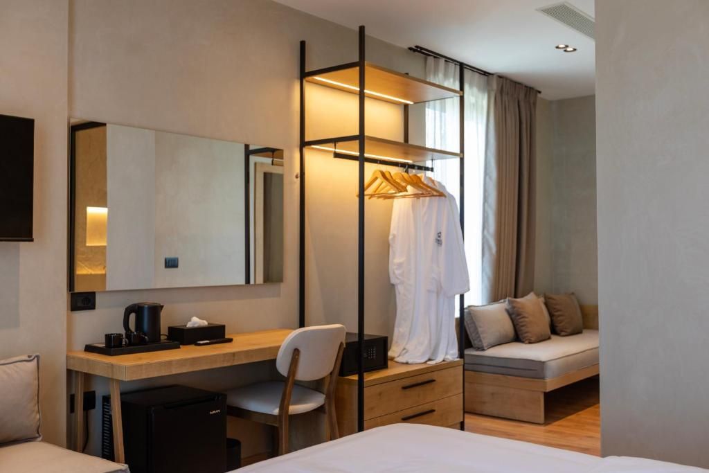 Una habitación de hotel con cama, escritorio y silla, armario, sofá y un espejo grande.