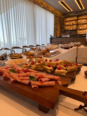 A buffet table with various food items and a stone wall in the background.