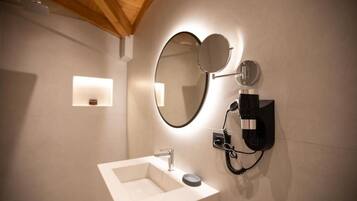 Un baño con un lavamanos blanco, un espejo y un teléfono instalado en la pared.