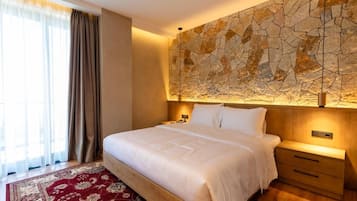 A hotel room with a large bed, a nightstand, a wall-mounted lamp, and a patterned rug.