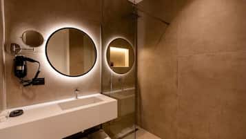 Un baño moderno con un espejo grande, un lavabo y una ducha.