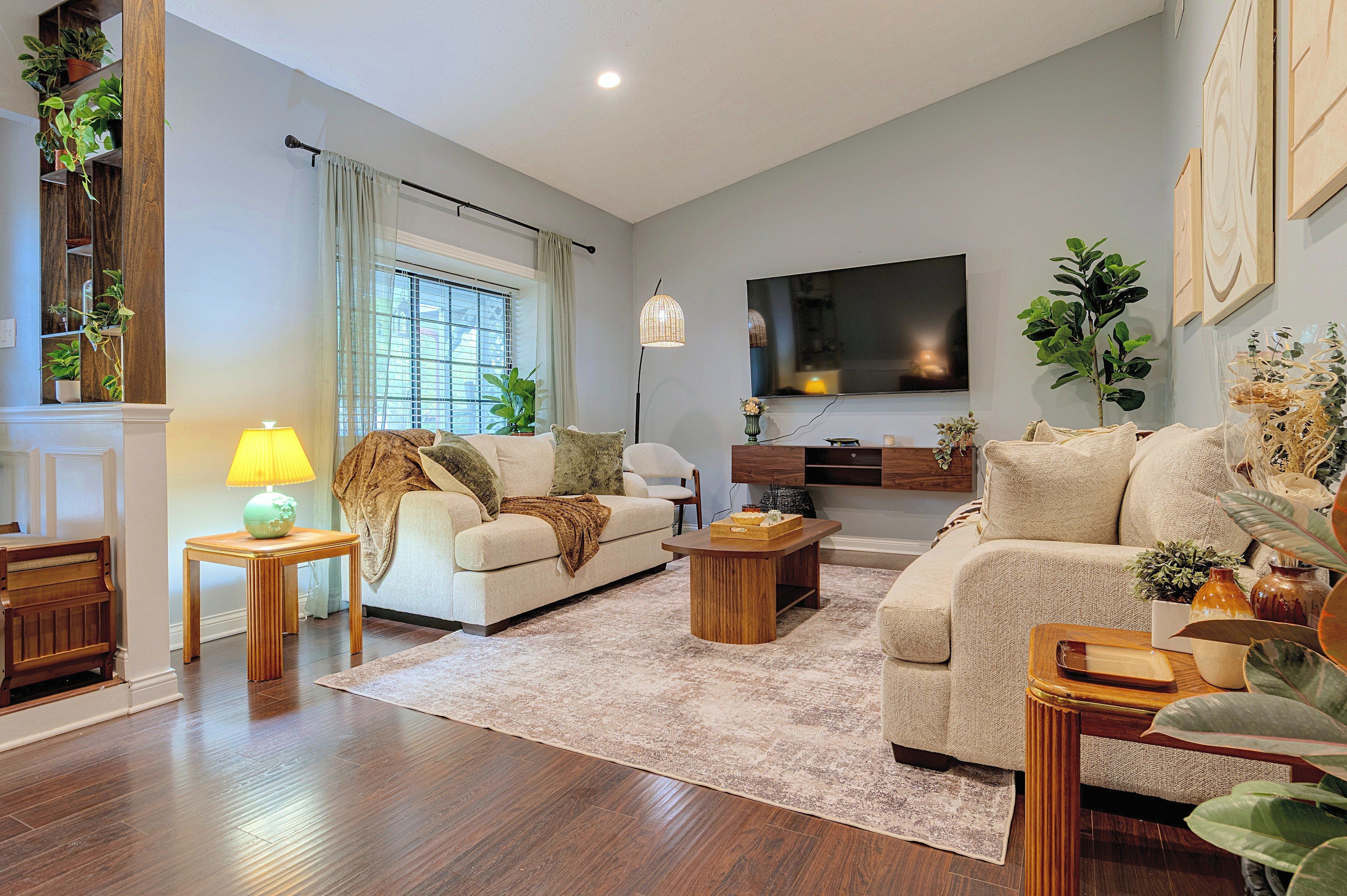 A living room with a sofa, coffee table, and a flat-screen TV mounted on the wall.