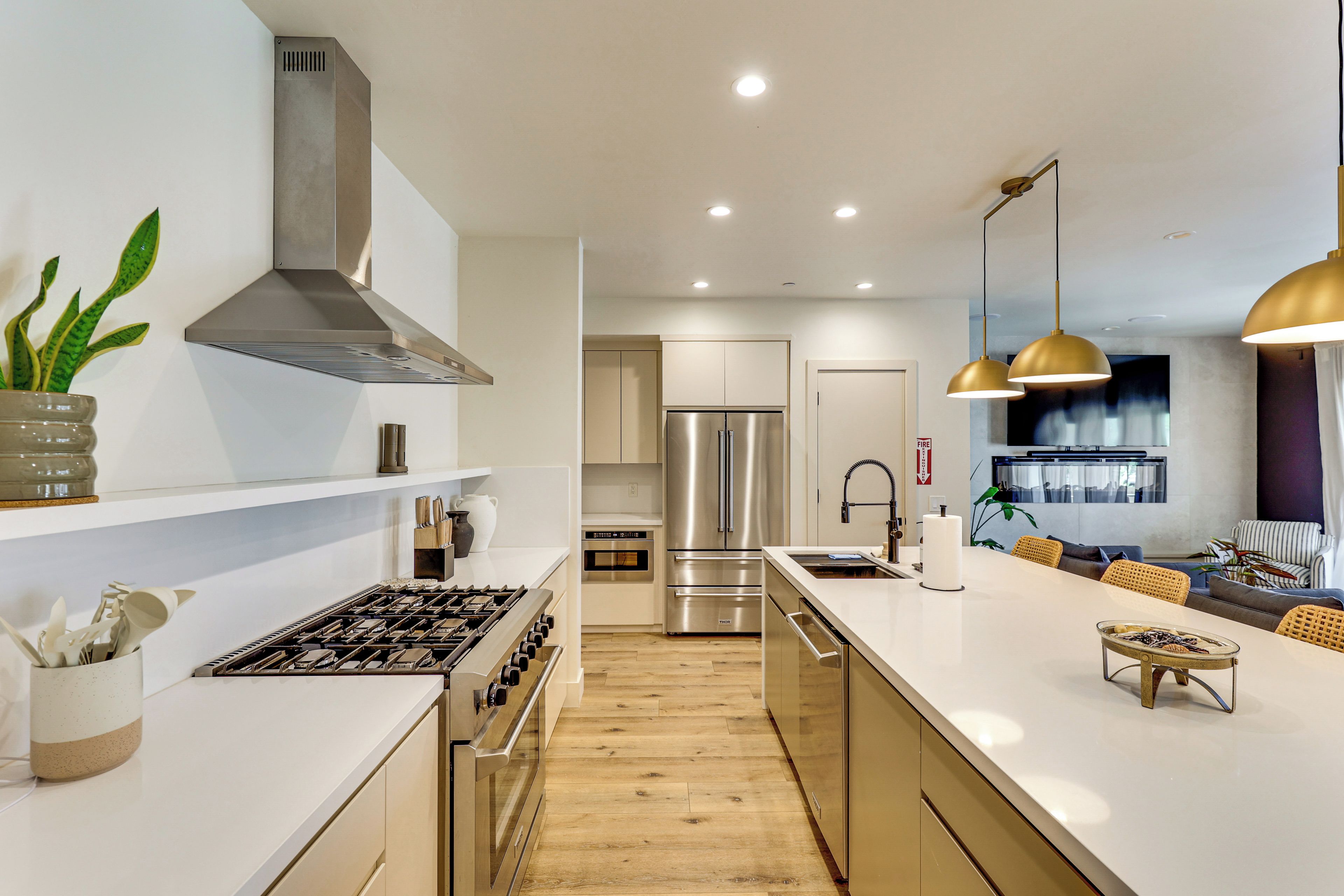 Een moderne keuken met een centraal eiland, roestvrijstalen apparatuur en hanglampen.