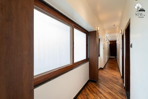 Un couloir d’hôtel avec un plancher en bois, de grandes fenêtres et une enseigne indiquant le nom de l’hôtel.