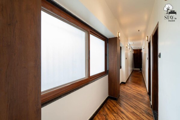 A hotel corridor with wooden flooring, large windows, and a sign indicating the hotel name.