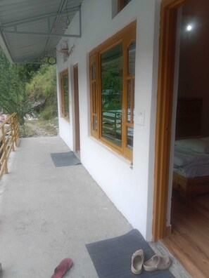 Una habitación con una cama, una puerta de madera y una ventana con vistas al verdor.