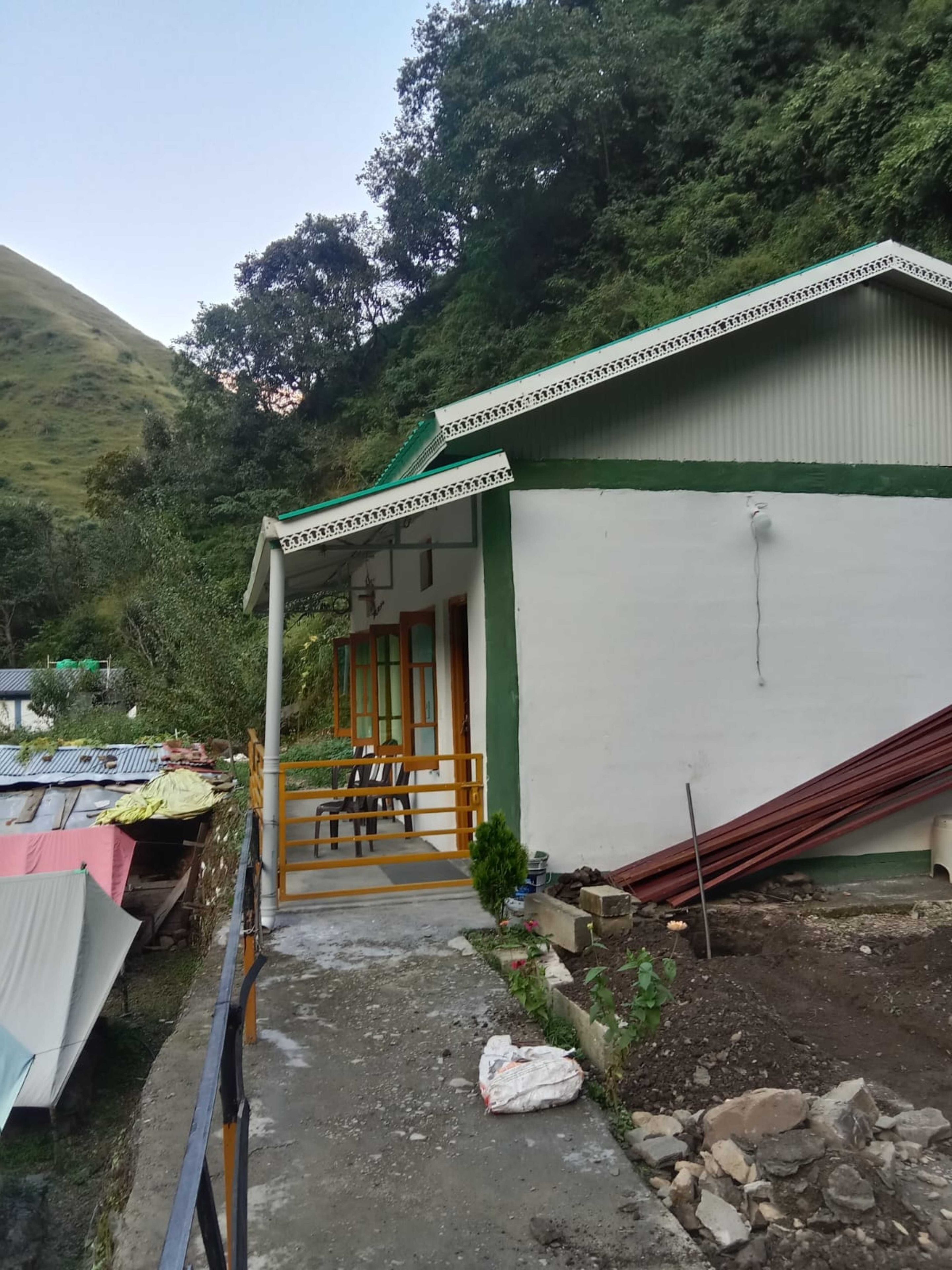 Un bâtiment doté d’un porche, d’un escalier menant à une porte, et dont les matériaux de construction sont éparpillés aux alentours.